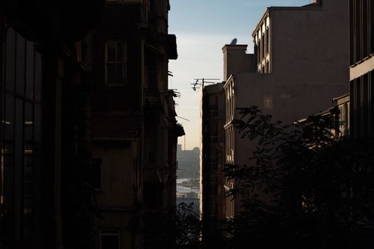 A silhouette of an alleyway in İstanbul with a cityscape view of the Bosphorus at dusk.