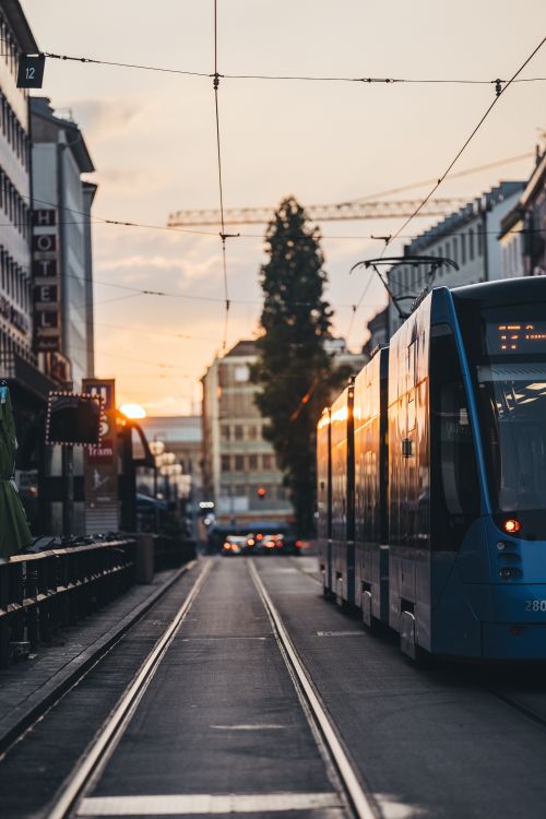 Free Urban scene with a tram on city tracks at sunset, capturing warm light reflections. Stock Photo