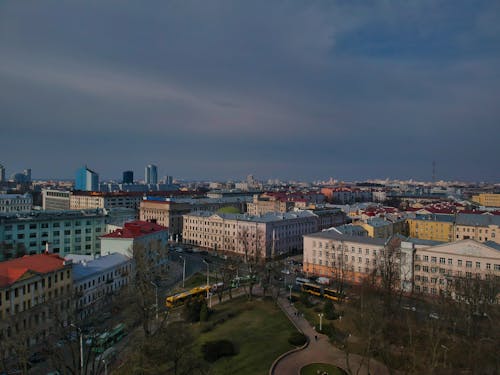 From above of city district with typical modern residential buildings and green park against cloudy blue sky