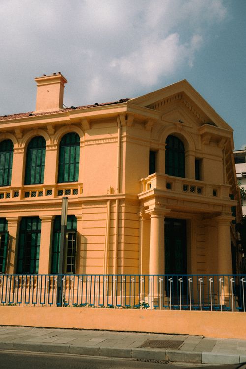 Free A historic yellow building with green accents stands under a vibrant sky. Stock Photo