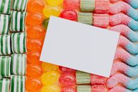 Closeup from above of white paper card composed on rows of delicious caramel gummy jelly sweets in modern candy shop