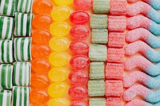 From above of various delicious jelly and caramel sweets arranged in rows by type and color in modern candy store