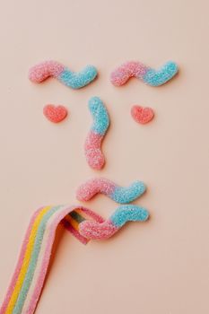 米色背景上，色彩缤纷的软糖被创意排列成一张俏皮的脸