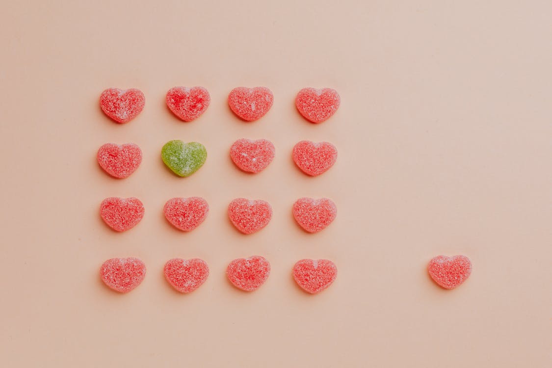 Free Top view of delicious sprinkled jelly sweets composed in lines with one candy aside on pink backdrop in candy shop Stock Photo