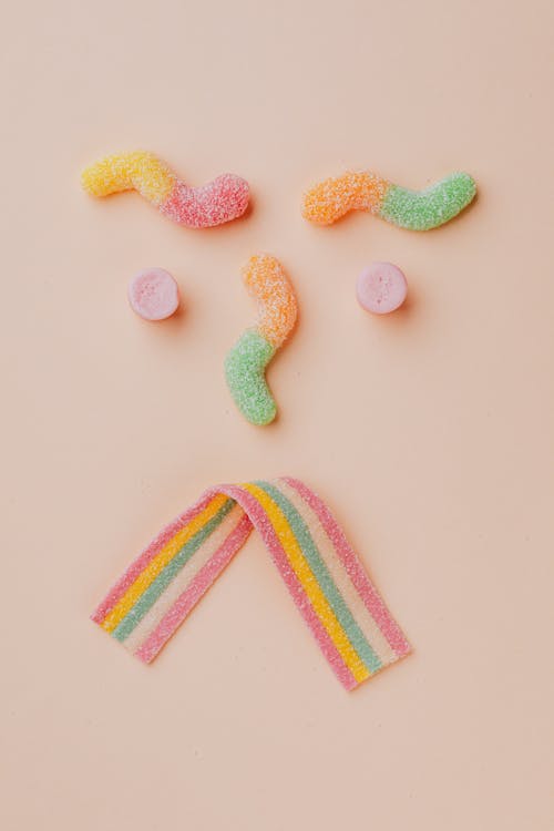 Upset face made of various gummy candies against beige backdrop