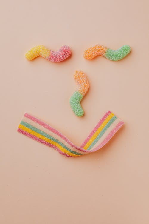 Top view flat lay composition of various colorful fruit jellies placed on pink background