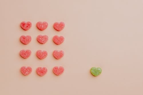 Flat lay composition of rows of delicious fruit jellies hearts placed on pink background