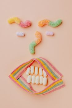 粉红色背景上，彩色糖果的艺术排列形成了一张脸