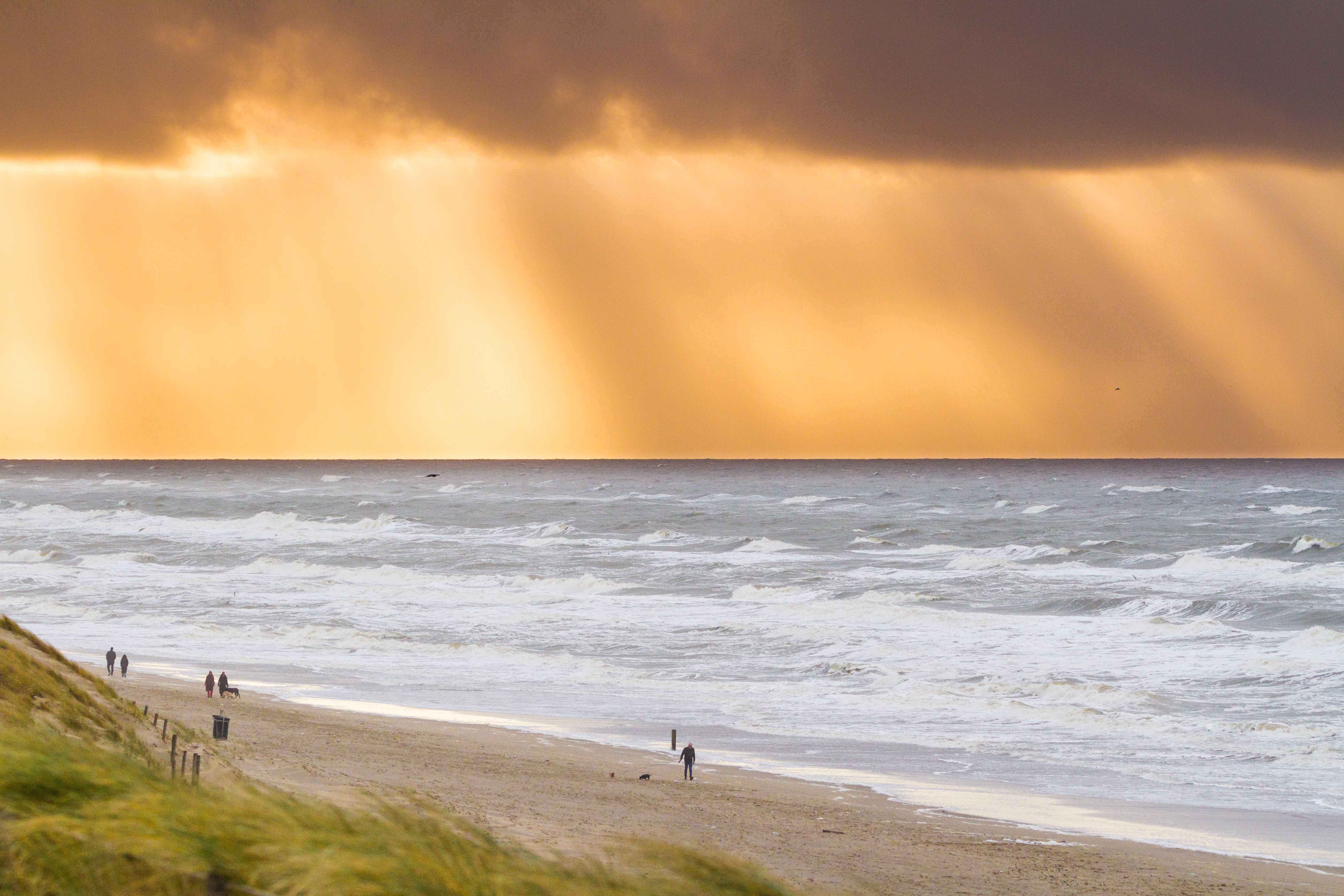 Sunset over Zandvoort Beach, North Holland, with dramatic clouds and waves.