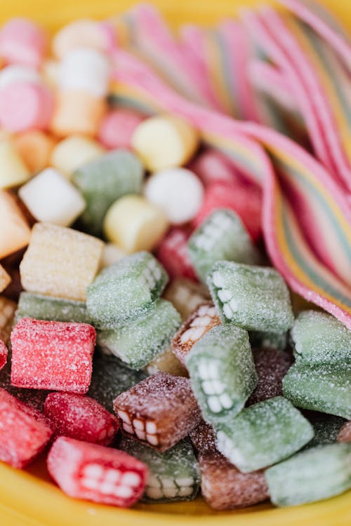 Free From above closeup of heap of multicolored tasty sweets placed in yellow plate Stock Photo