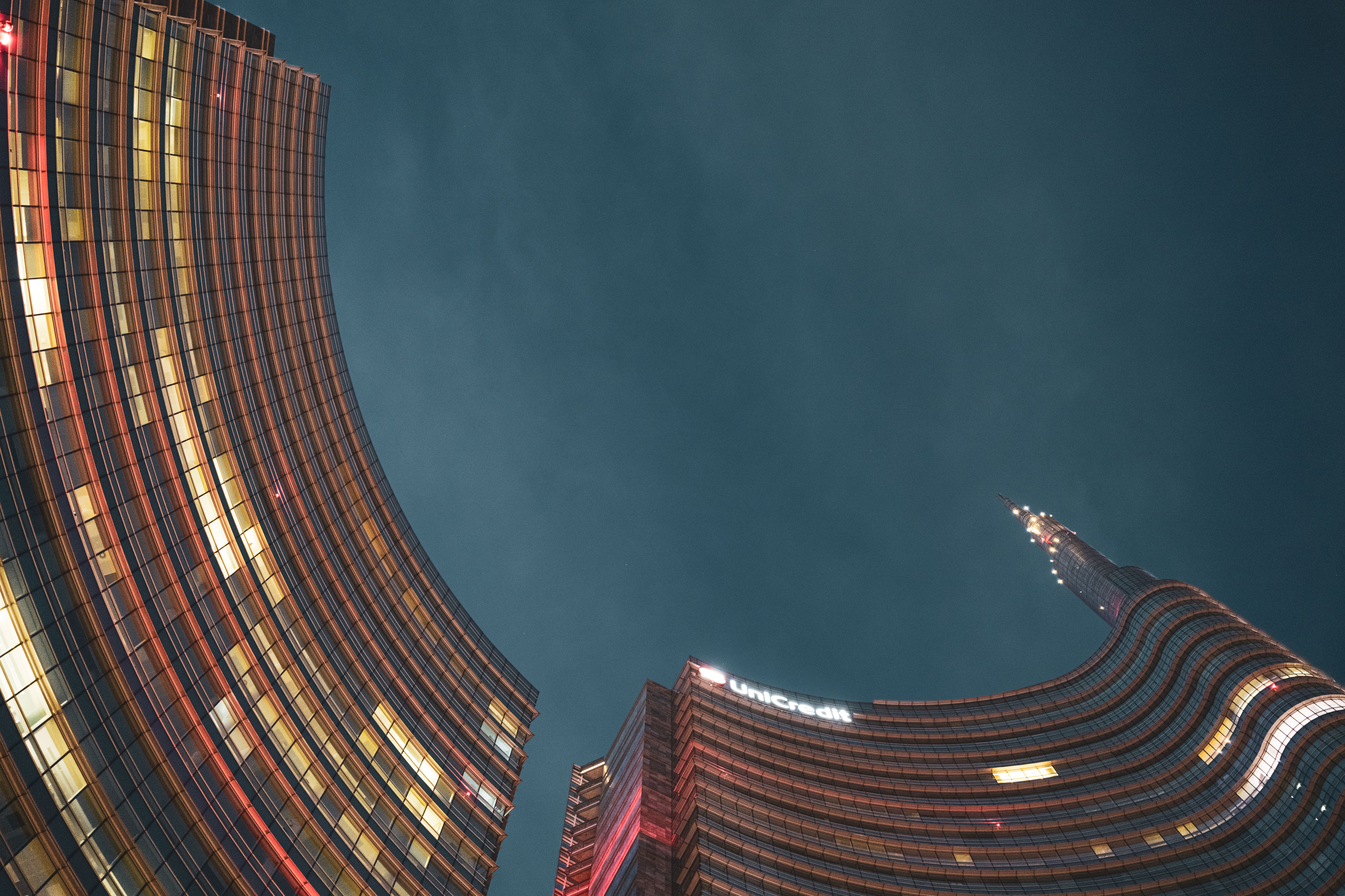 Stunning night view of UniCredit Tower in Milan, showcasing vibrant architecture and city skyline.