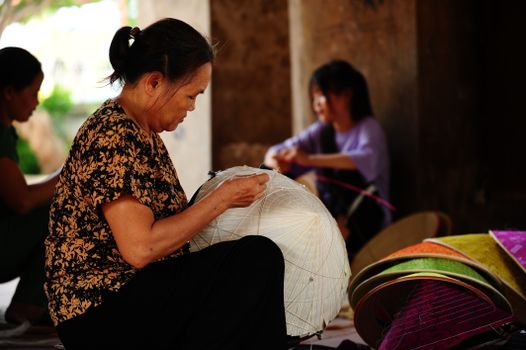 A woman skillfully crafting traditional lanterns by hand in an artisan workshop.