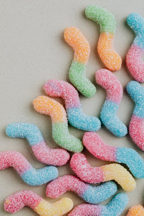 Top view of multicolored worm shaped marmalade arranged on grey background