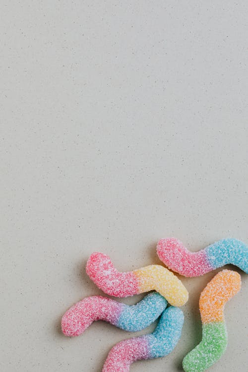 Colorful gummy worms on grey background
