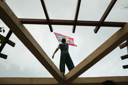 Free A person waving a political flag through a geometric structure in a protest setting. Stock Photo