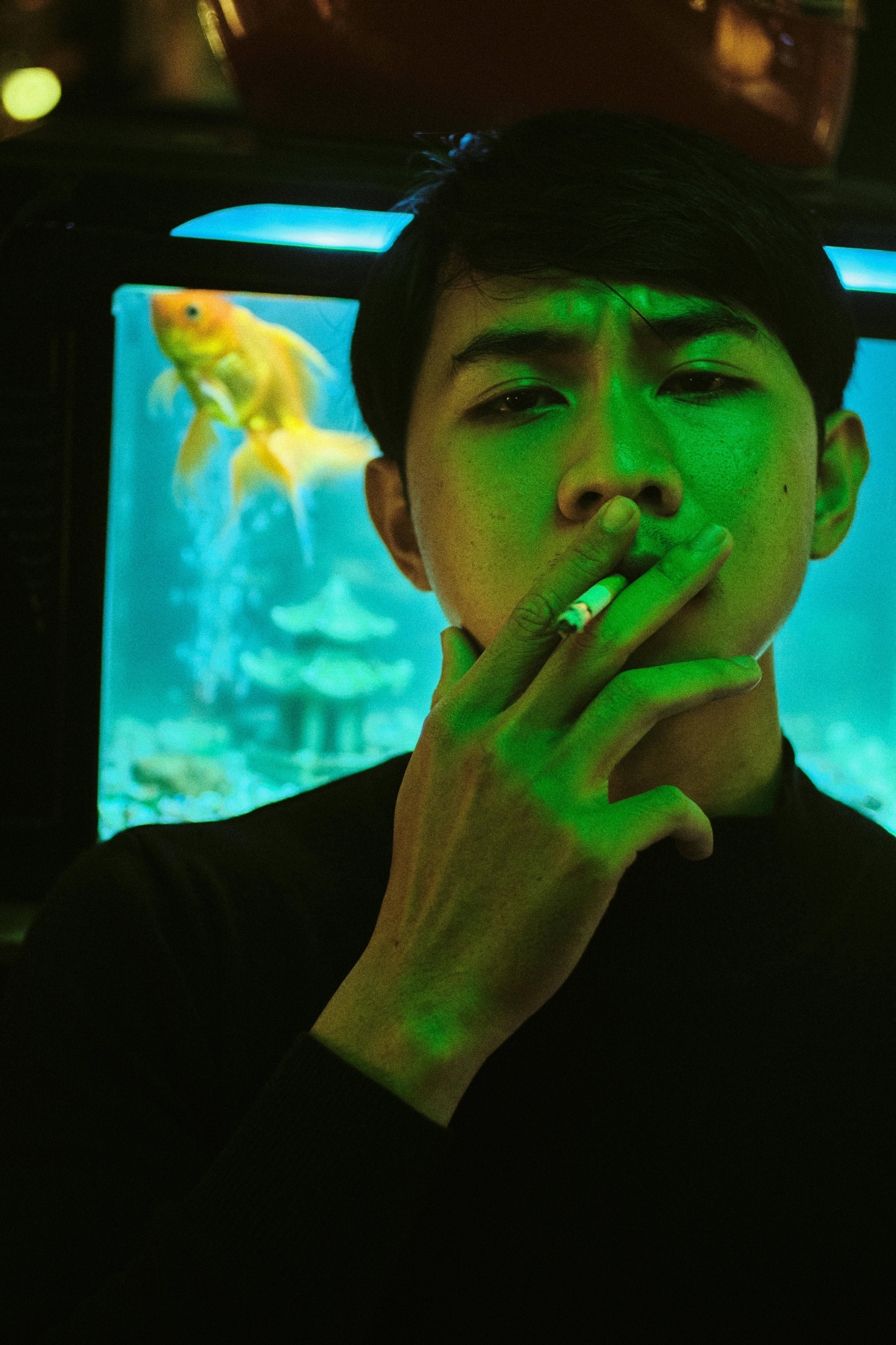 pensive asian man smoking cigarette at night