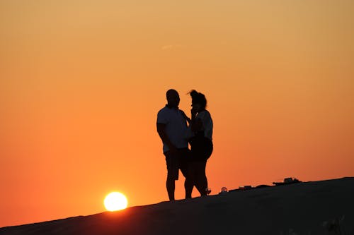 Silhouette of Couple Standing on Top of Mountain during Sunset