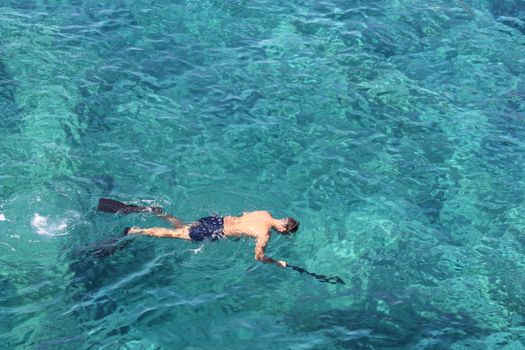 An adult male snorkeler explores vibrant turquoise waters in a tropical location, capturing the essence of summer leisure.