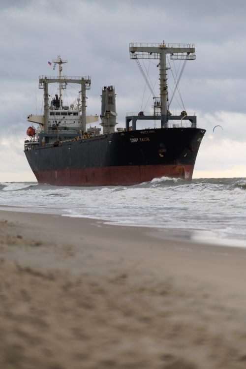 Free Stranded cargo ship on a sandy beach, Kaliningrad Oblast, Russia, under cloudy skies. Stock Photo