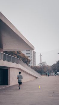 一名男子在雅加达的混凝土道路上慢跑，背景是国家纪念碑