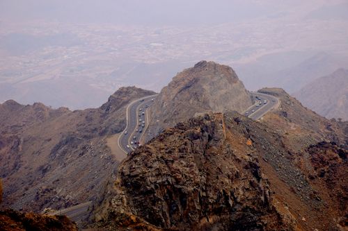 Free A winding mountain road carved through rugged rocky peaks offers breathtaking views. Stock Photo