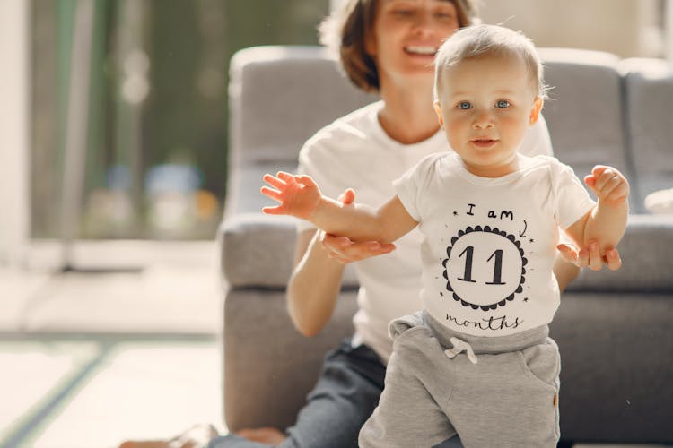 Happy Mother Helping Baby To Walk At Home