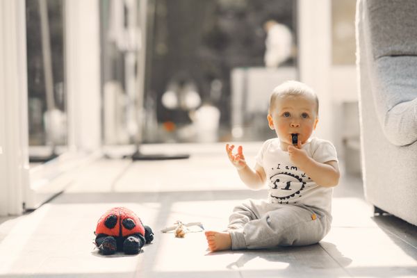 A small child playing happily with a toy on a sunlit floor. Photo by Gustavo Fring on Pexels