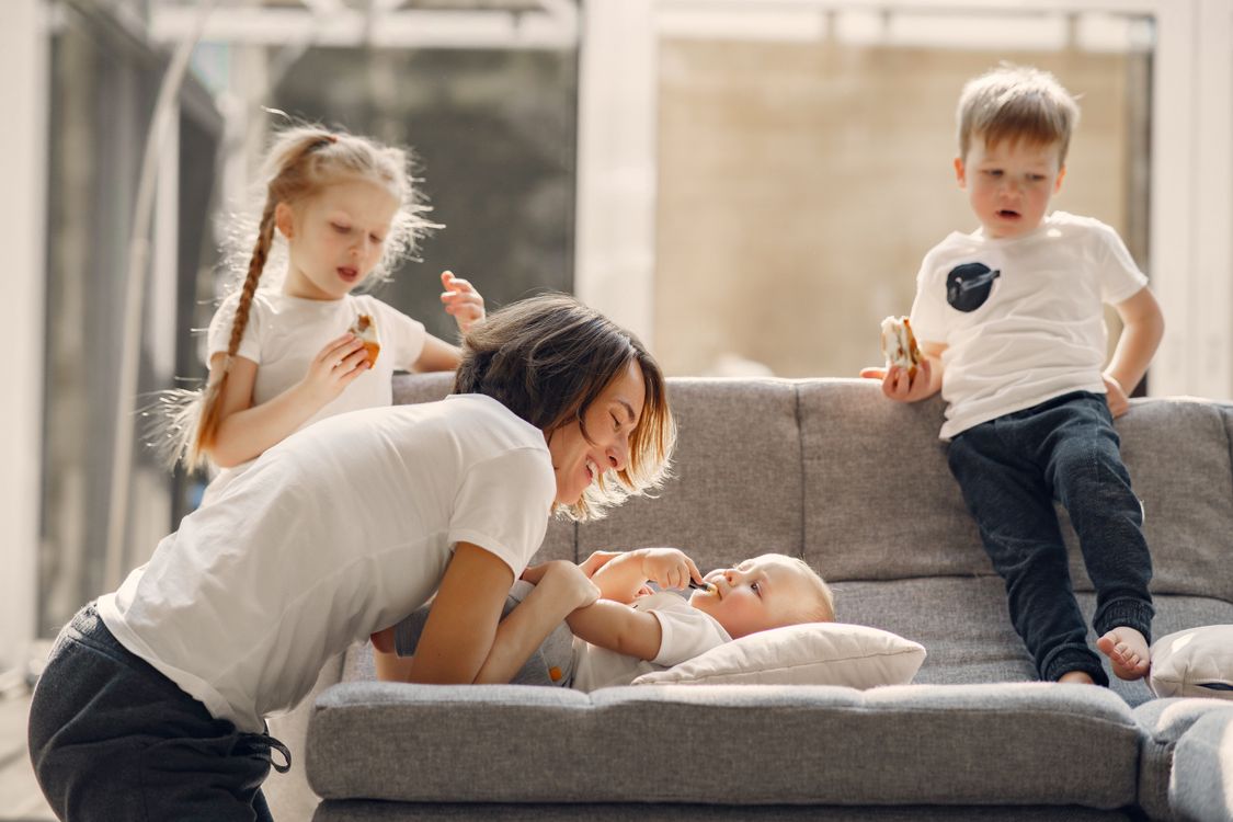 A mother playing warmly with her toddler while other children look on