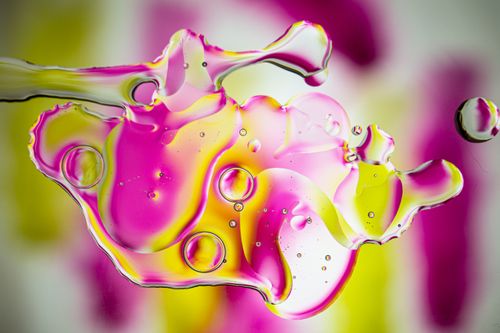 Free Colorful abstract art with oil droplets on water creating dynamic patterns in pink, yellow, and green hues. Stock Photo