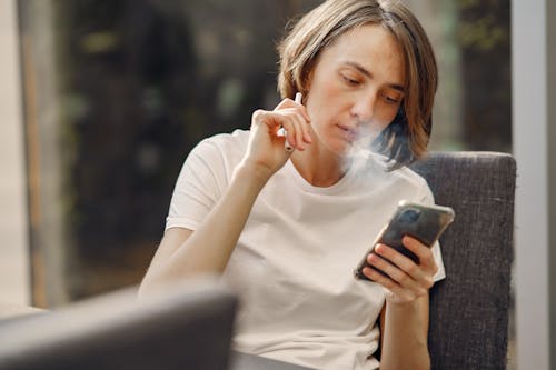 Free Woman Smoking while Holding Her Phone Stock Photo