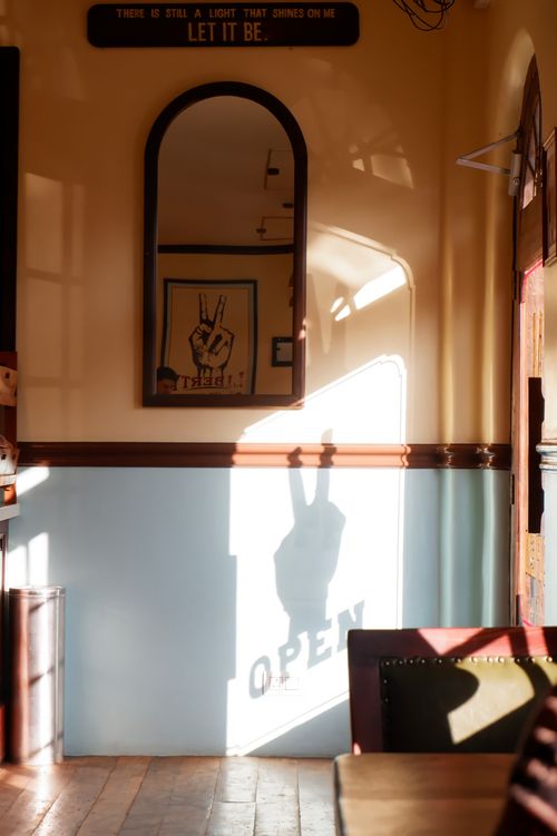 Free A sunlit room with a peace sign shadow and retro decor, creating a nostalgic mood. Stock Photo