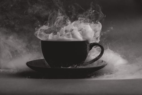 Free A steaming hot beverage in a black cup with dramatic vapor and moody ambiance. Stock Photo