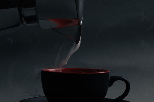 Free Close-up of hot coffee being poured into a cup from a moka pot with steam rising. Stock Photo