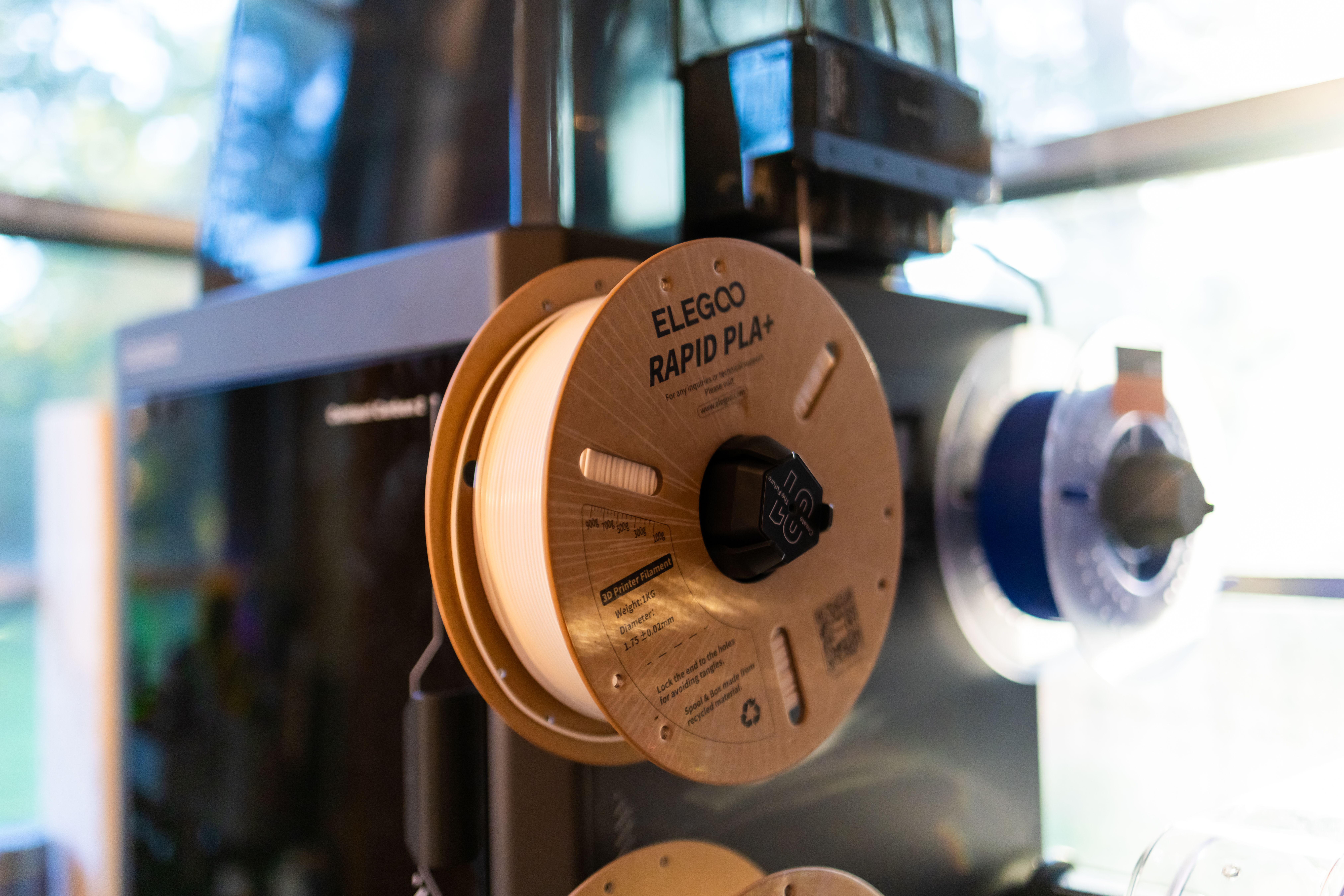Close-up view of a 3D printer with Elegoo Rapid PLA+ spool, ideal for tech enthusiasts.