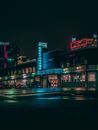 灰狗公交车站的夜间场景充满活力，城市环境中点缀着霓虹灯标志
