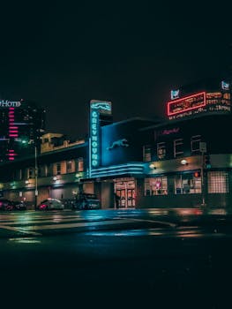 灰狗公交车站的夜间场景充满活力，城市环境中点缀着霓虹灯标志