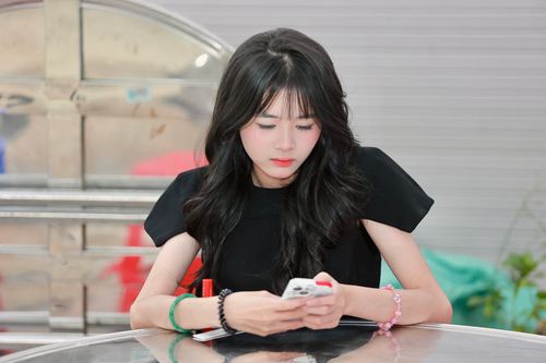 Free Young woman in black dress intently using her smartphone at a cafe table. Stock Photo