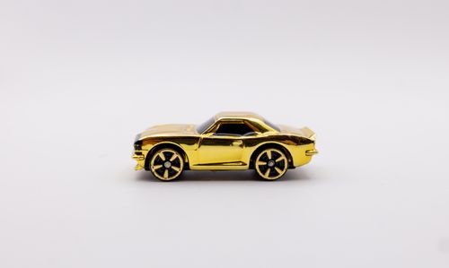 Free Close-up of a shiny golden toy car model on a clean white backdrop. Stock Photo