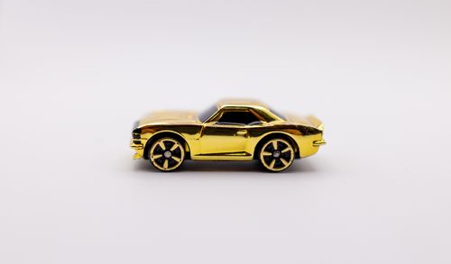 Free Close-up of a shiny golden toy car against a minimalistic white background for product photography. Stock Photo