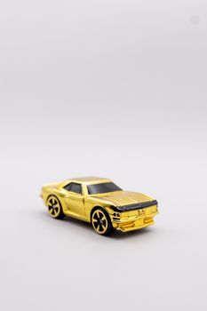 A sleek golden toy model car isolated on a minimalist light gray background, showcasing a modern design.