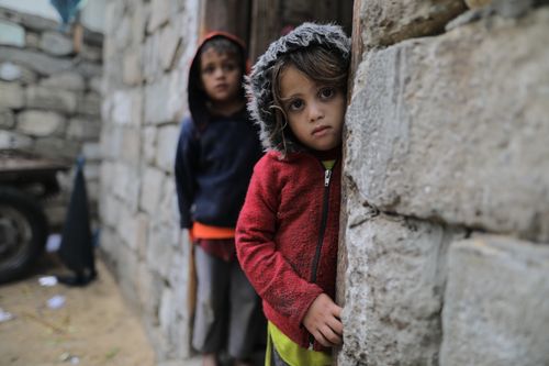 Free Two young children in a rustic, stone-built outdoor setting, exuding curiosity and innocence. Stock Photo