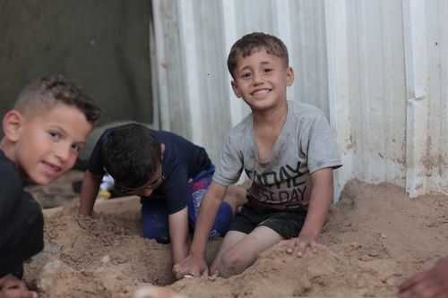 Free Three boys having fun digging in the sand in an outdoor environment. Stock Photo