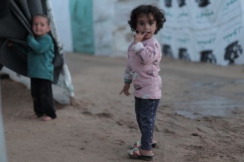Free Two young children in a refugee camp, standing outdoors on a sandy path. Stock Photo