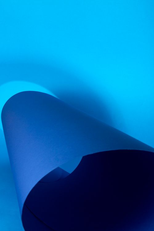 Free An abstract image featuring a rolled blue paper with a smooth gradient background. Stock Photo