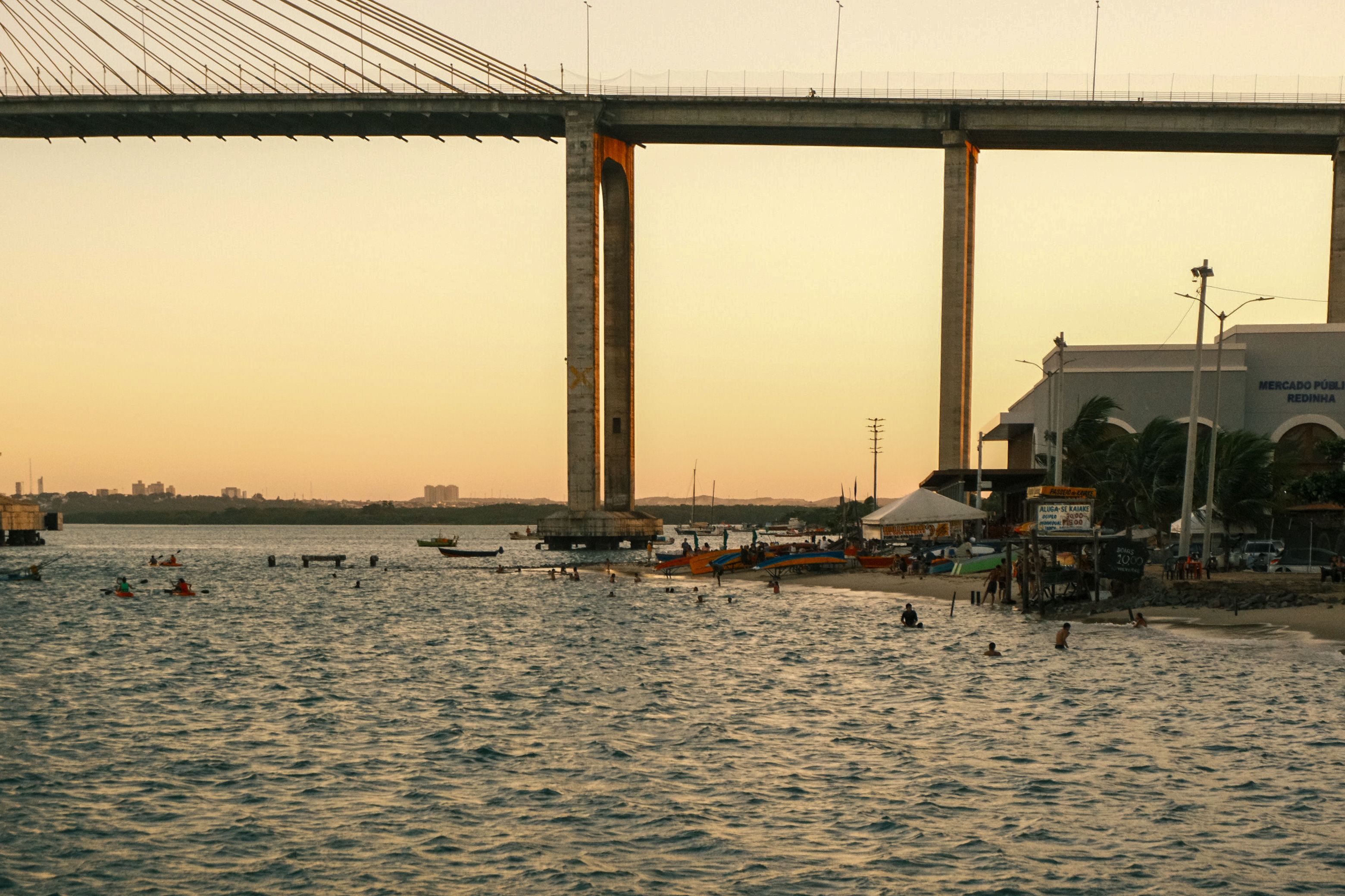 Scenic view of Newton Navarro Bridge during sunset in Natal, Brazil, with people enjoying the beach.