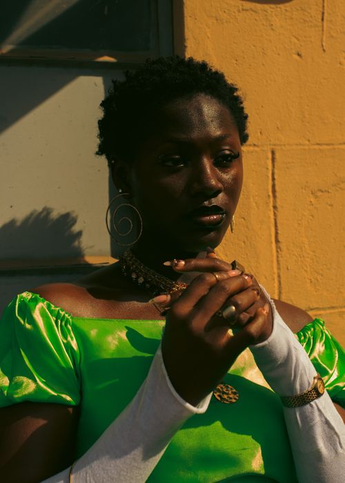Free A captivating portrait of a woman in vibrant fashion against a yellow wall. Stock Photo