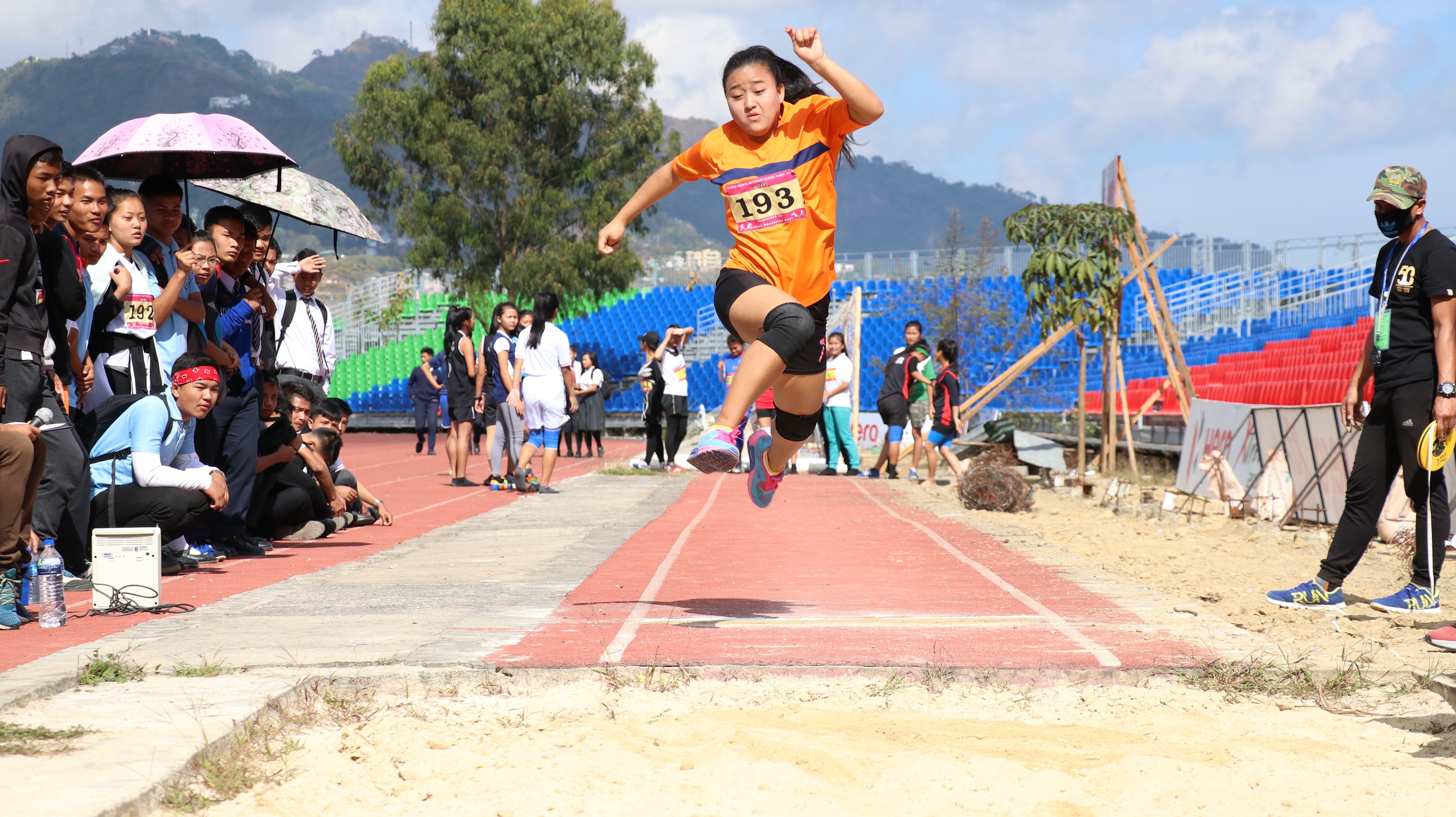 A female athlete competes in a long jump event at a sunny day sports meet in Mizoram, India.
