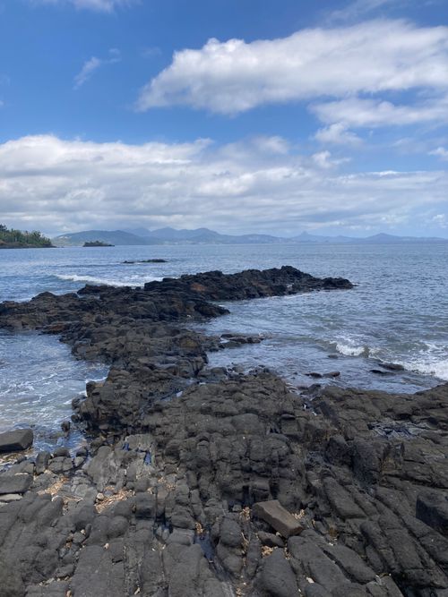 Free Breathtaking view of a rocky shoreline extending into a vast ocean under a clear sky. Stock Photo