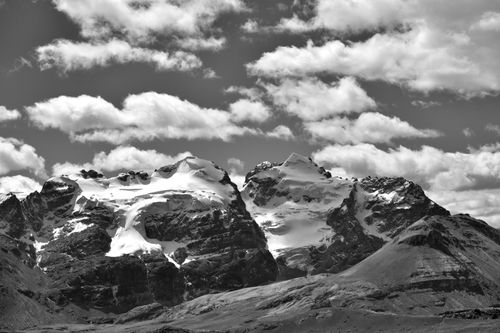 Free Black and white image capturing the snow-capped peaks of Cordillera Blanca under a dramatic cloudy sky in Peru. Stock Photo