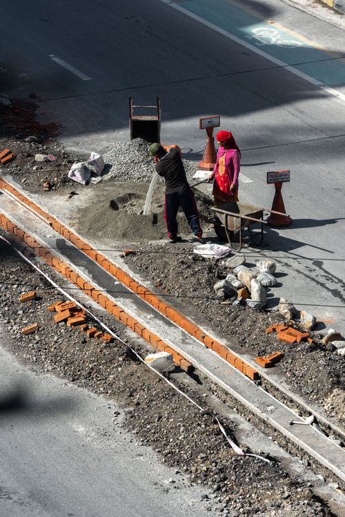 Free Two workers labor on a bustling city roadway construction site. Stock Photo